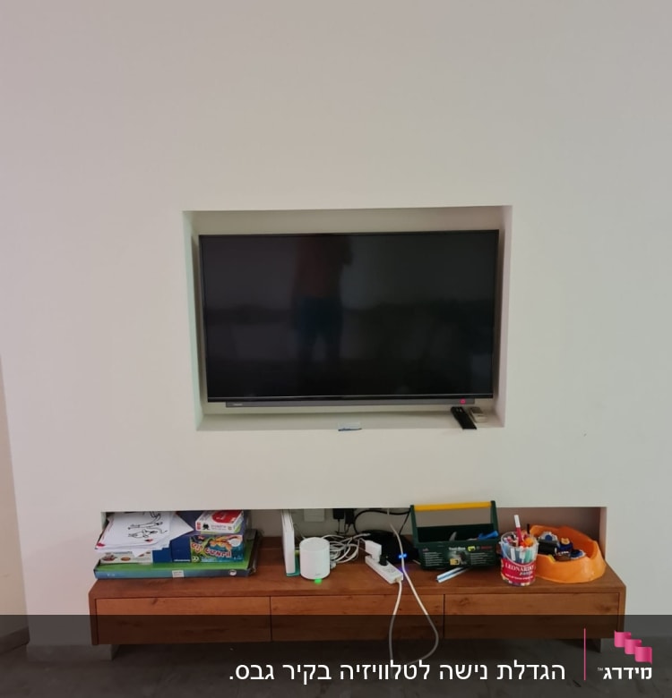 טלוויזיה מותקנת בקיר גבס עם מדף עץ מתחת